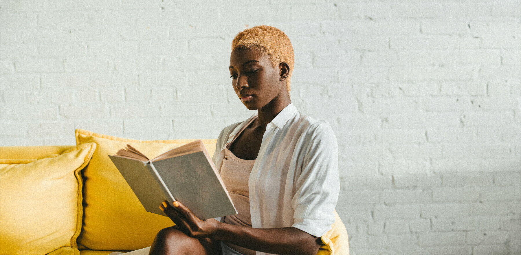woman reading on couch with cool hair and excellent posture